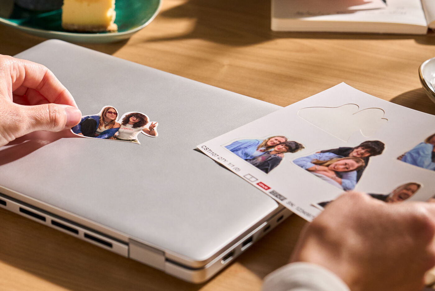 Eine Hand platziert einen personalisierten Freiform Sticker auf einem Laptop.
